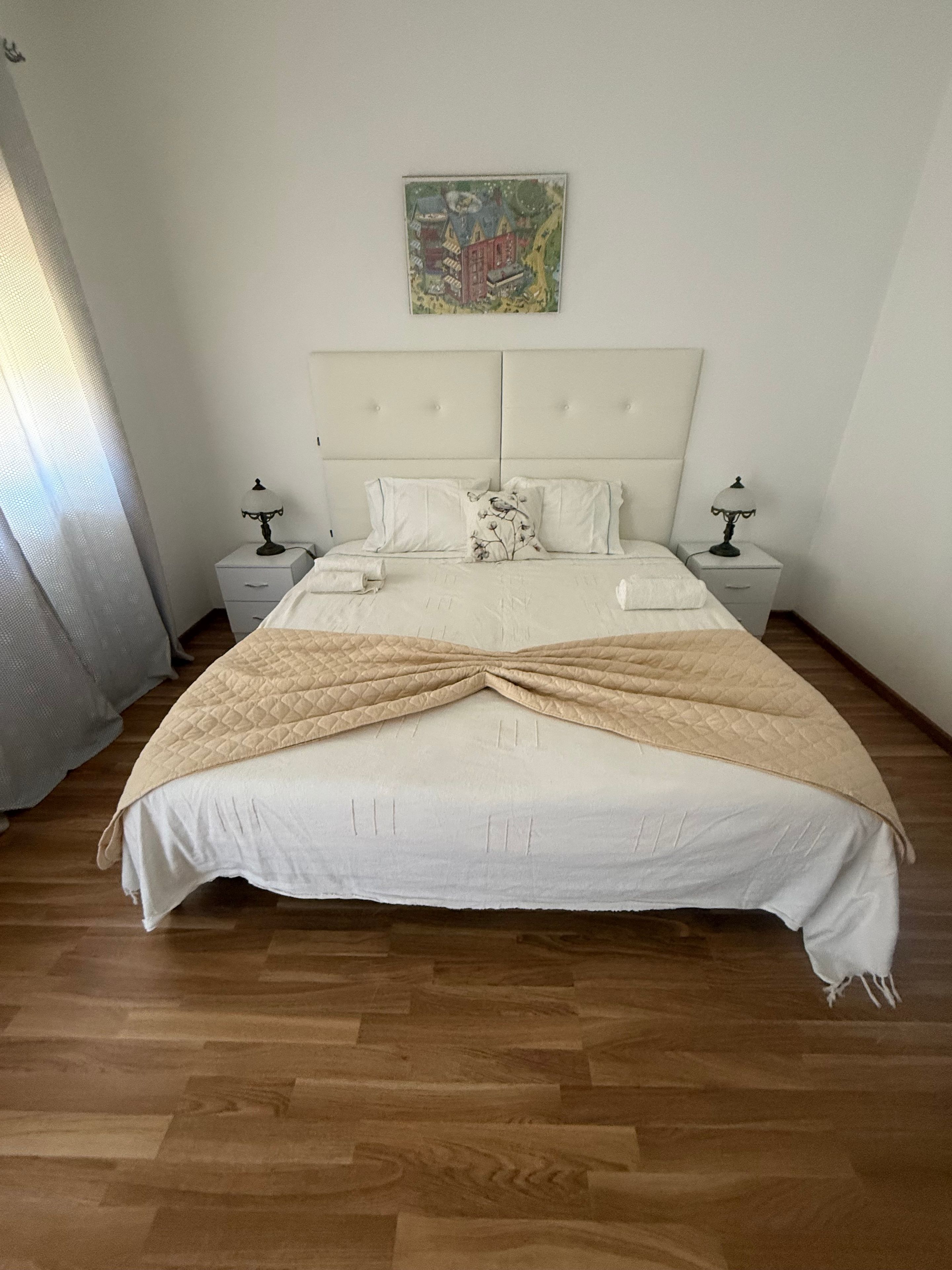 A bed with a quilt, two bedside tables, and a wall-mounted artwork.