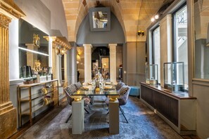 Un espace repas avec une table en verre, des chaises blanches et des éléments décoratifs dorés.