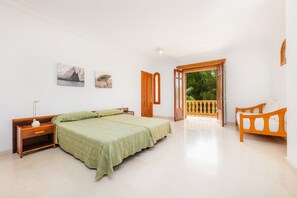 Une chambre à coucher avec un lit, une table de chevet, une lampe et une vue sur un balcon.