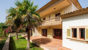 A two-story house with a balcony, a tiled patio, and a well-maintained lawn.