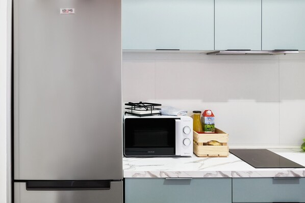 A kitchen with a stainless steel refrigerator, a microwave, and a wooden crate with bottles. - Apartment 'El Ático De Entrevías' with Wi-Fi (León)