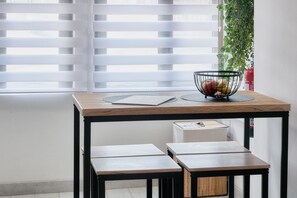 A table with a bowl of fruit, a placemat, and a box underneath.