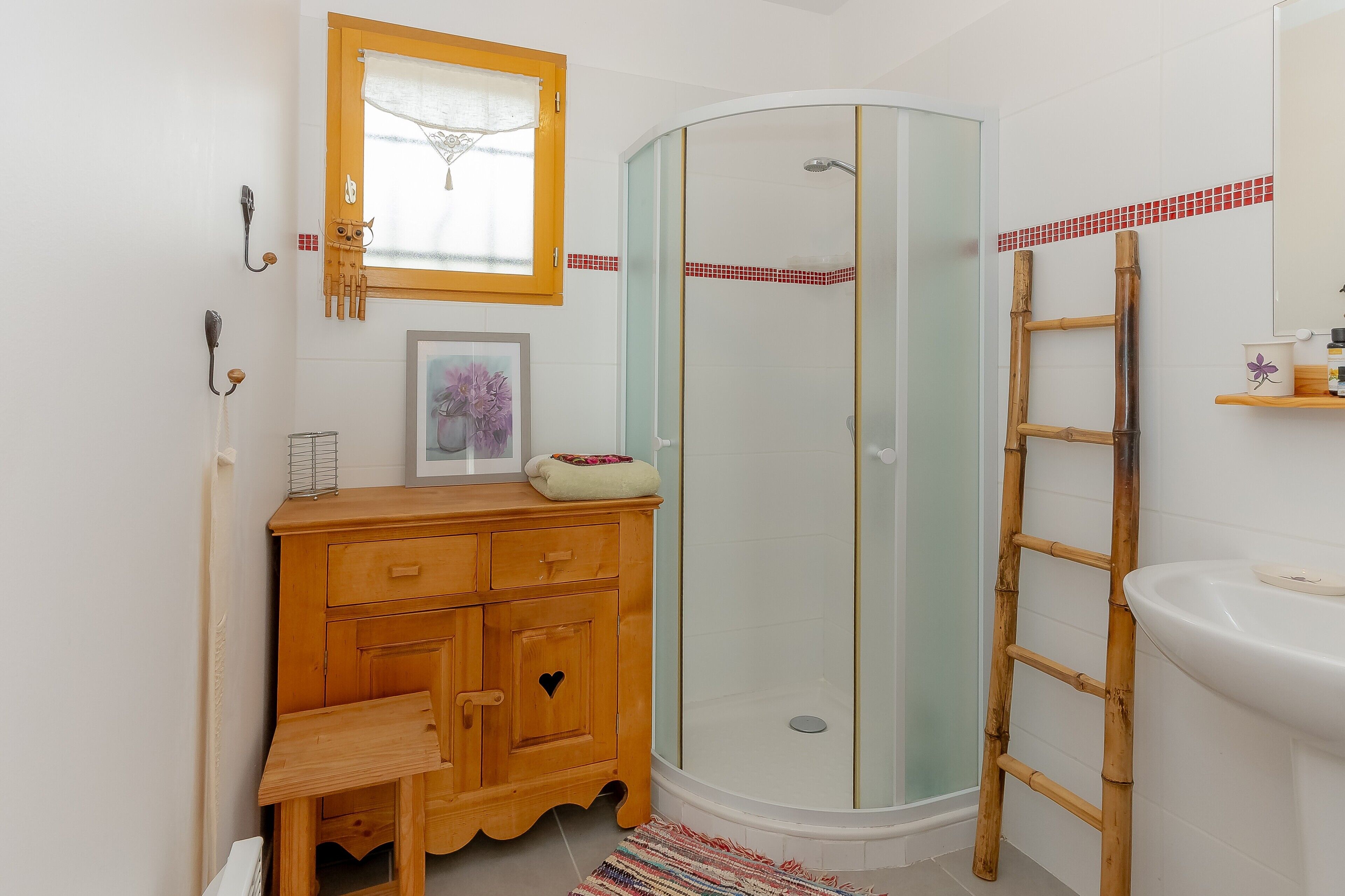 A bathroom with a wooden vanity, a glass shower enclosure, a white sink, and a wooden ladder.
