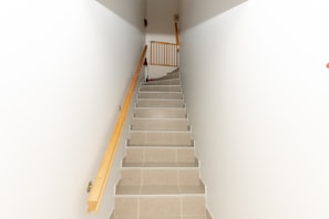 A staircase with wooden handrails and beige tiles.