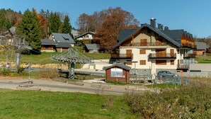 A chalet-style building with a balcony, a small wooden structure, and a clear sky. - Apartment "Gentiane" with Mountain Views, Private Terrace, and Wi-Fi (Les Deserts)