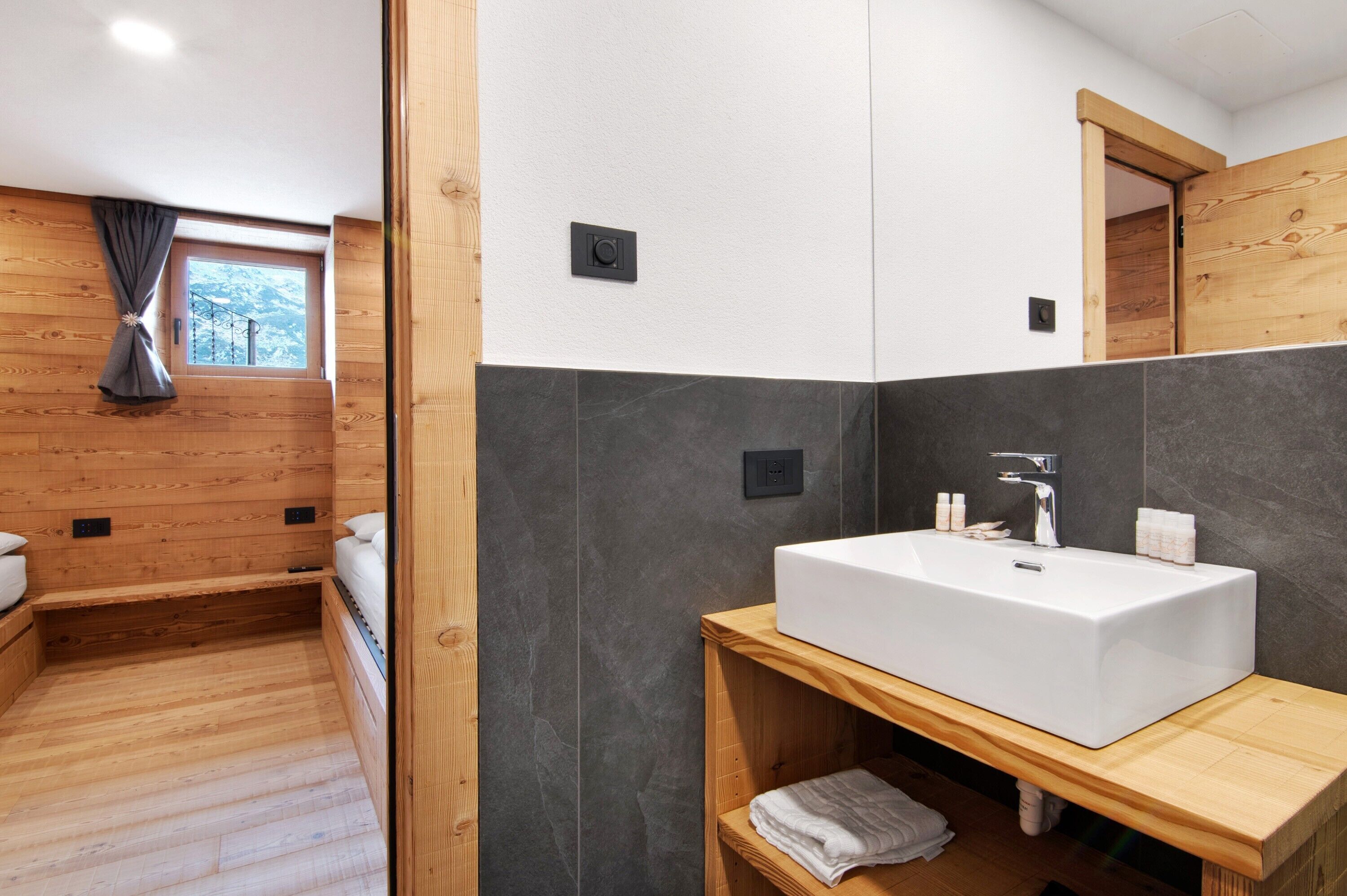 Un baño moderno con un lavamanos grande de color blanco, suelo de madera y una ventana con vistas.