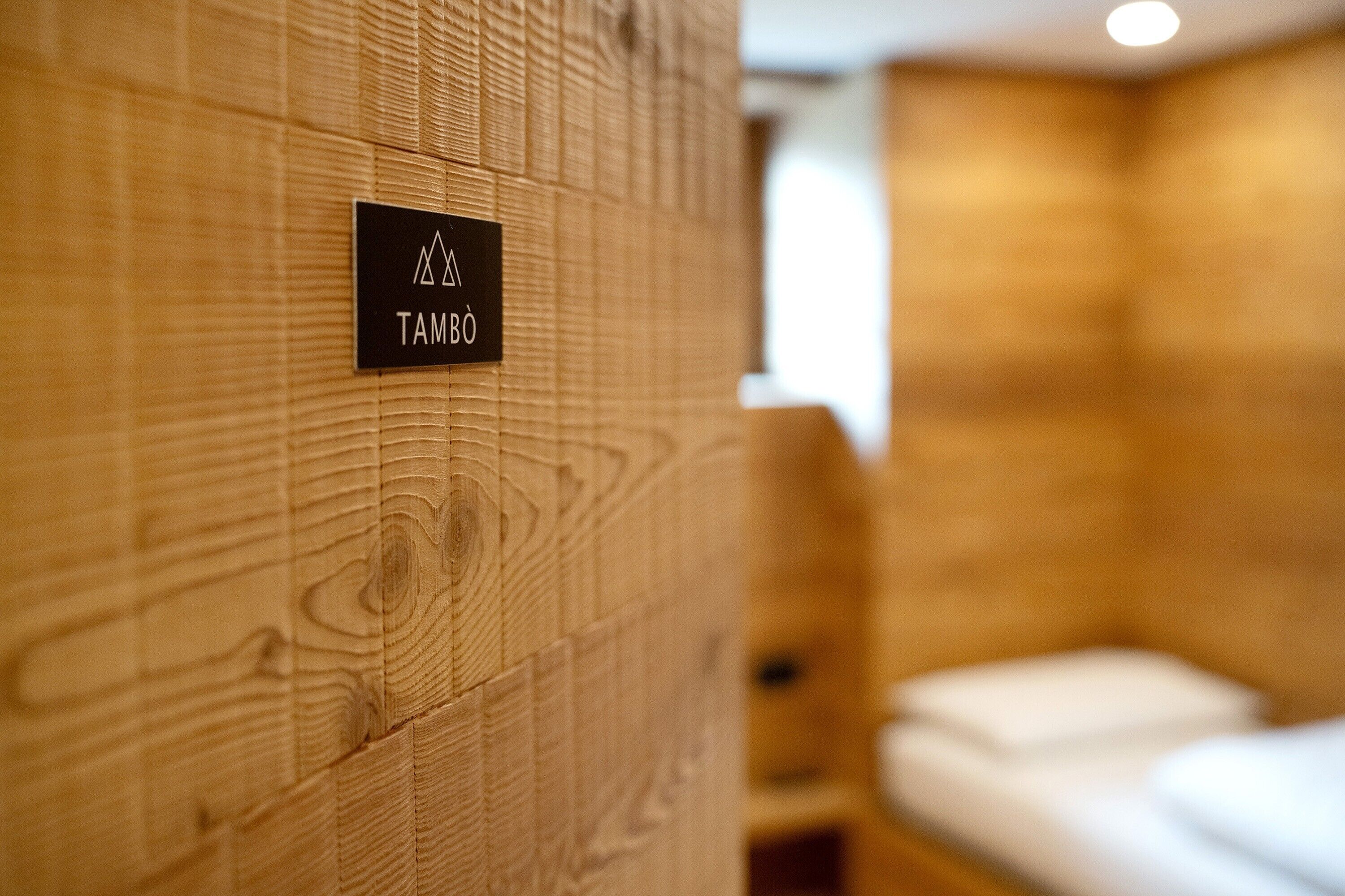 A wooden wall with a sign reading 'TAMBO' and a blurred room in the background.