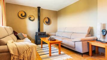 A living room with a sofa, a wooden coffee table, a patterned rug, a fireplace, and wall decor.