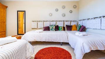 A hotel room with two beds, a large mirror, a red rug, and decorative wall art.