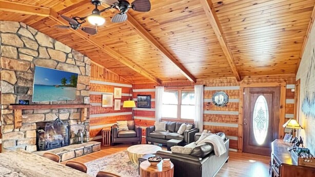 Ein geräumiges Wohnzimmer mit Kamin aus Stein, Holzboden und einer großen Steinwand.