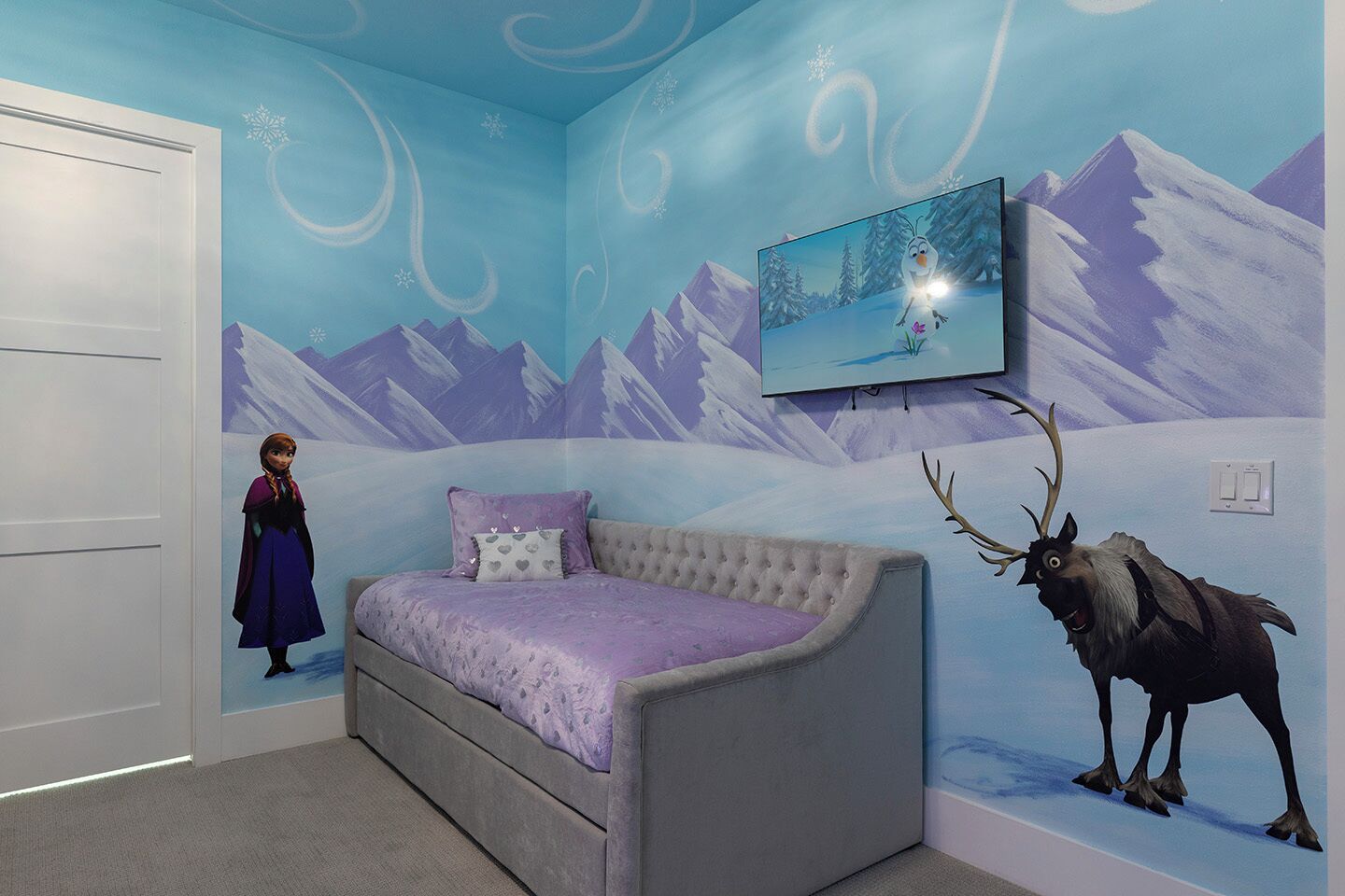 Ein Schlafzimmer mit Bett, Fernseher und Wandbild einer verschneiten Berglandschaft.