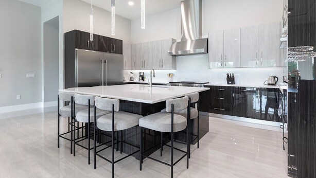 A modern kitchen with a central island, bar stools, stainless steel appliances, and pendant lighting. - The Commodious Chateau-TT452 (Kissimmee)