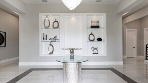 A modern interior with a glass table in the center, surrounded by minimalist decor on white shelves. - The Commodious Chateau-TT452 (Kissimmee)