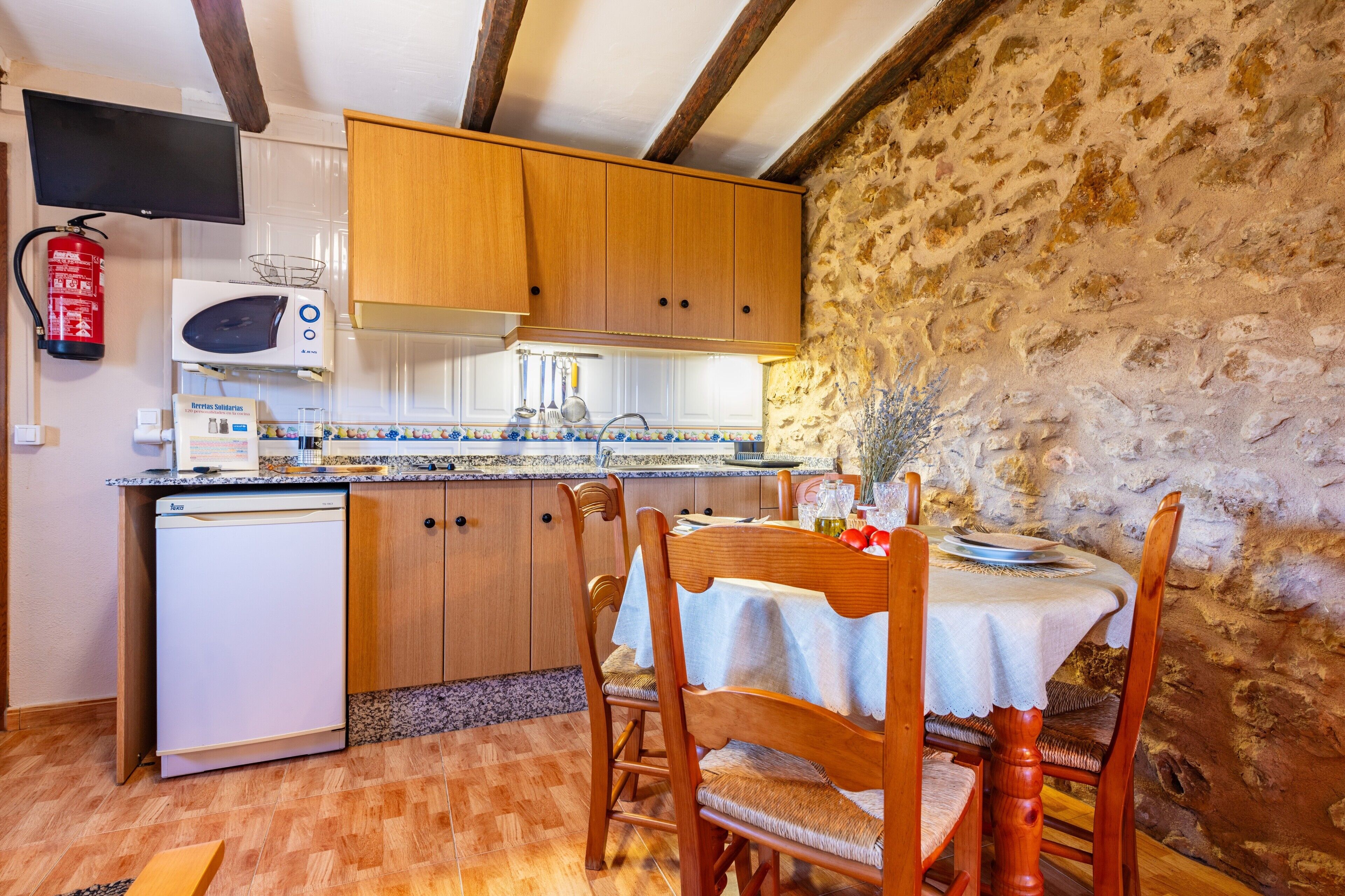 Une cuisine compacte dotée de meubles en bois, d’un four à micro-ondes, d’un évier et d’un coin repas avec une table et des chaises.