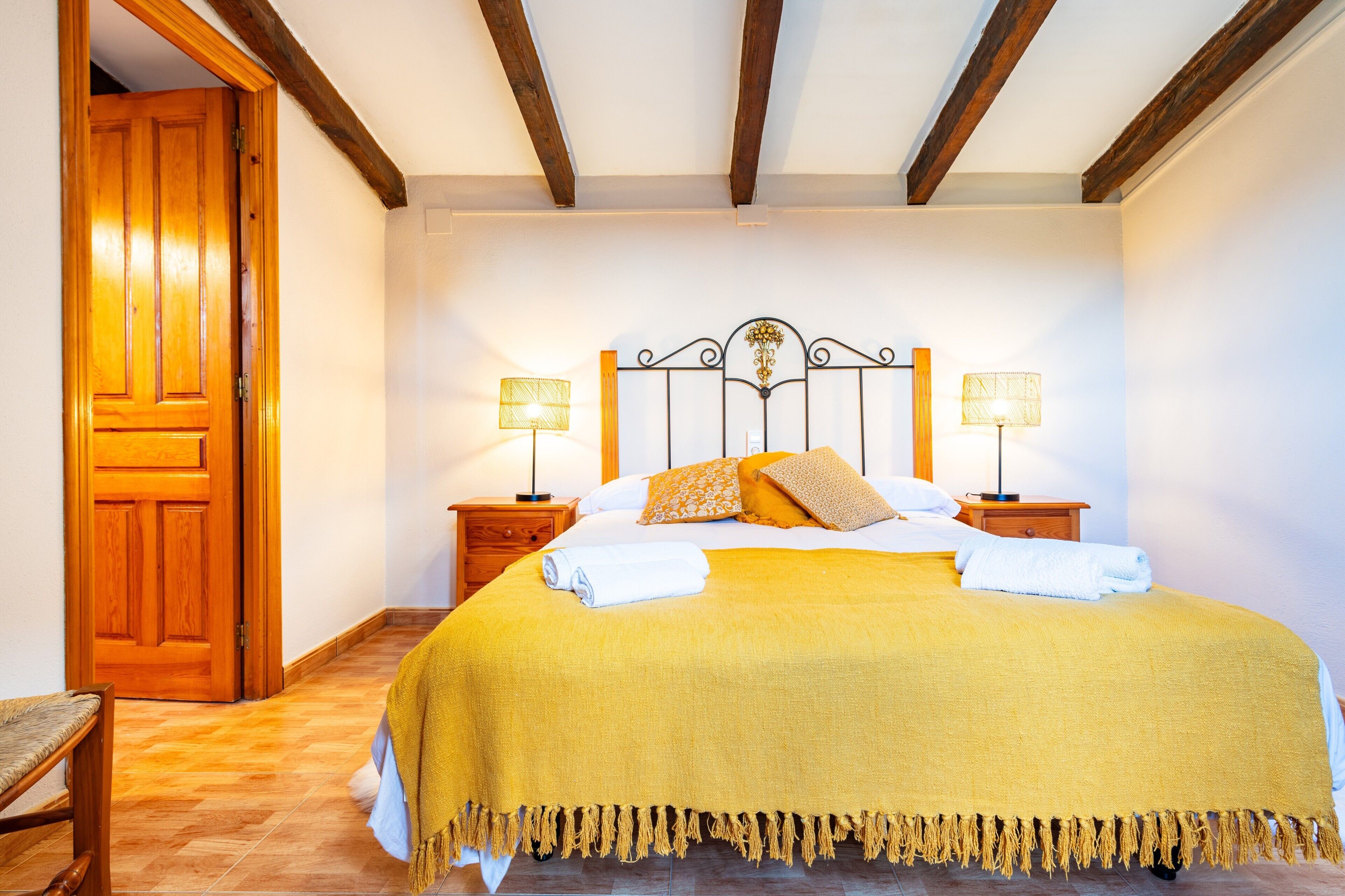Ein Schlafzimmer mit einem Bett, zwei Nachttischlampen, einer Holztür und einem Holzstuhl.
