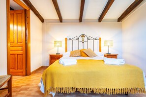 Un dormitorio con una cama, dos lámparas de noche, una puerta de madera y una silla de madera.