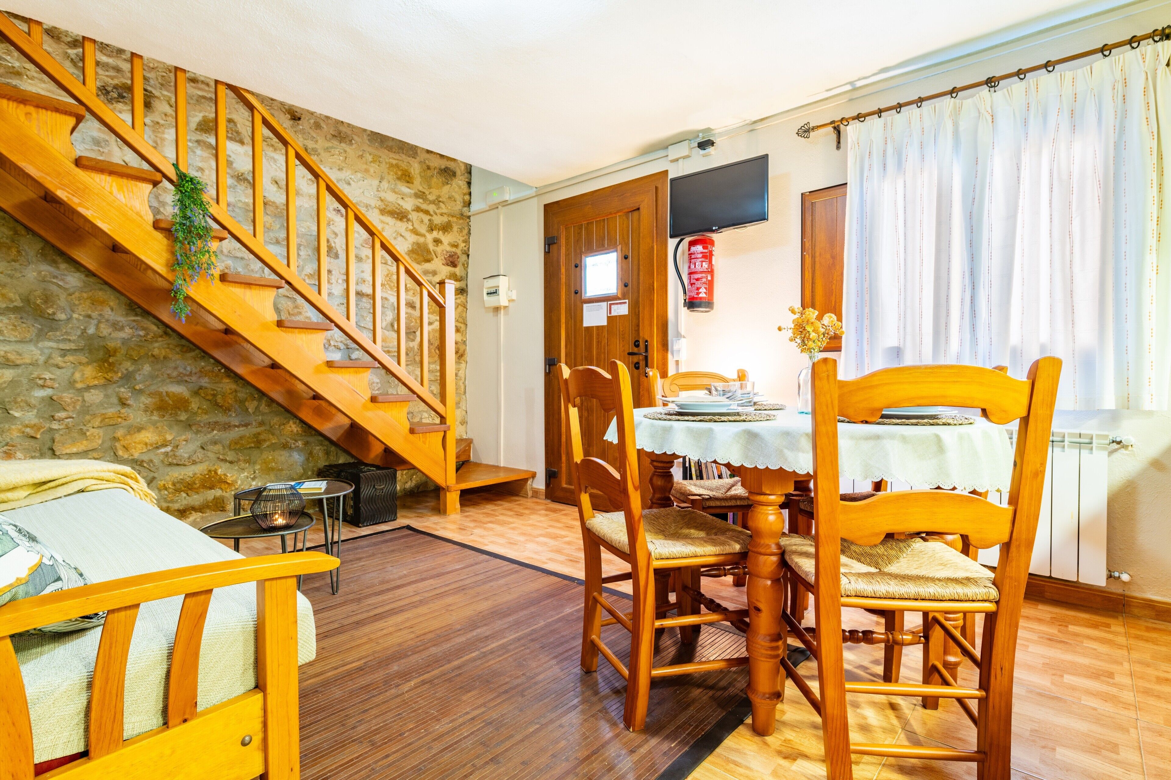 Un comedor con una mesa de madera, sillas y una escalera.
