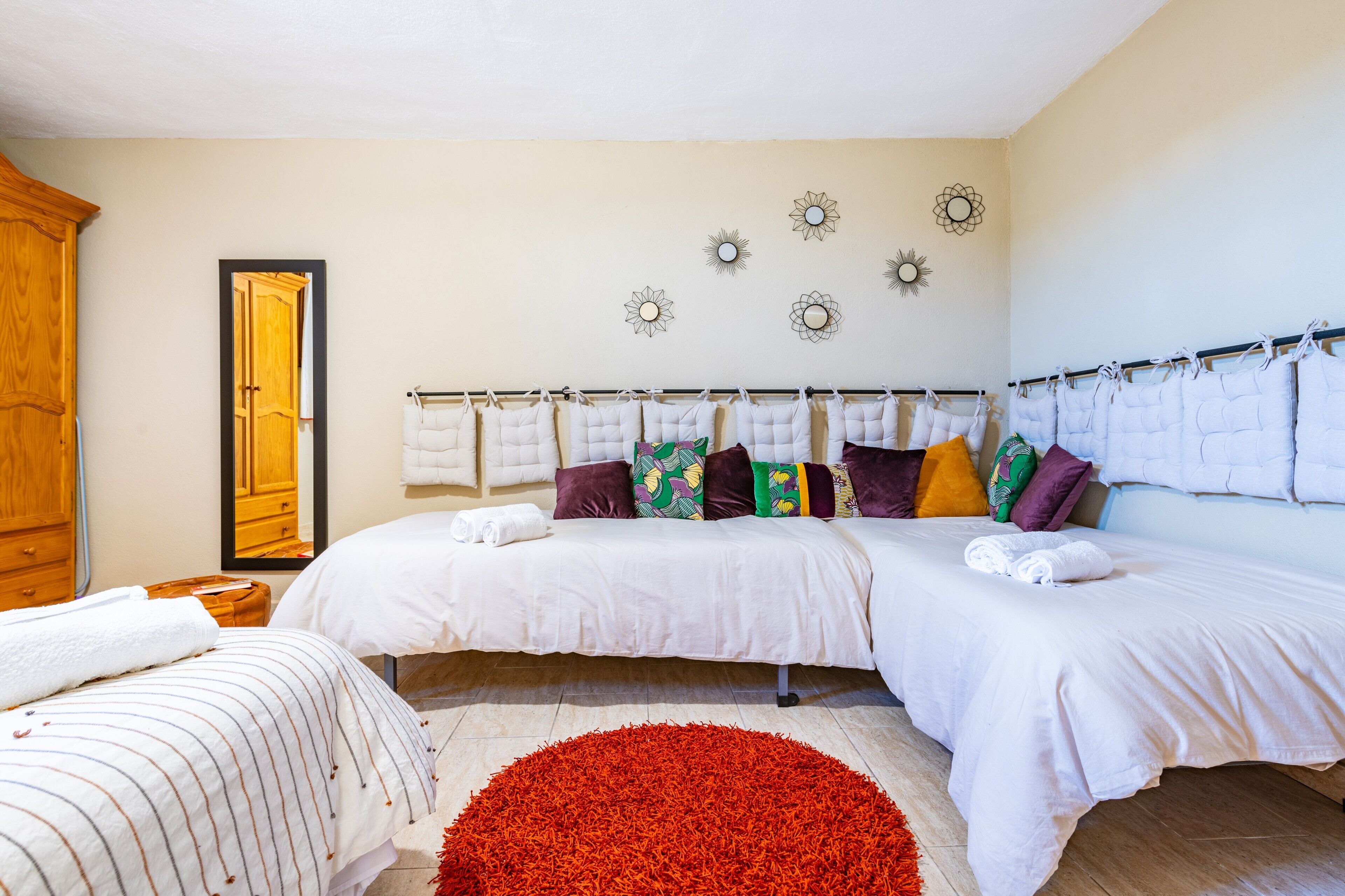A hotel room with two beds, a large mirror, a red rug, and decorative wall art.