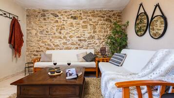 Una sala de estar acogedora con una pared de piedra, una mesa de centro de madera, un sofá blanco y una planta.