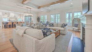 A spacious living room with a fireplace, a dining area, and large windows. - Fourth Green Getaway by Sandpiper | Near Beach (Seabrook Island)