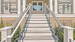A staircase with a metal railing leading to a door with a window. - Fourth Green Getaway by Sandpiper | Near Beach (Seabrook Island)