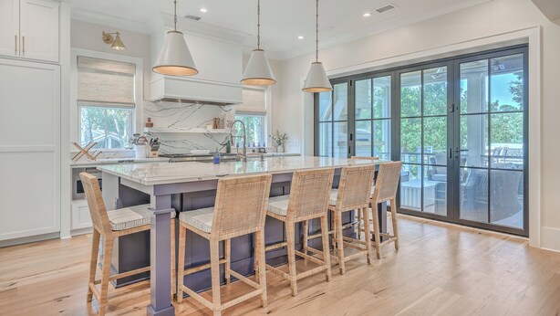 A modern kitchen with a large island, pendant lighting, and a view to the outdoors. - Fourth Green Getaway by Sandpiper | Near Beach (Seabrook Island)