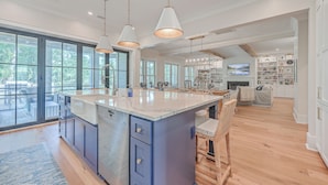 A spacious kitchen with a large island, pendant lighting, and a view of the outdoors. - Fourth Green Getaway by Sandpiper | Near Beach (Seabrook Island)