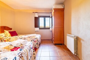 A bedroom with two beds, a wardrobe, a window, and a radiator. - Rural House 'Arinesa B' with Mountain Views, Private Terrace and Wi-Fi (Culla)