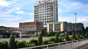 A multi-story building with a prominent Mitsubishi Motors sign, surrounded by greenery and a white fence. - LA Hotel Tawau (Tawau)