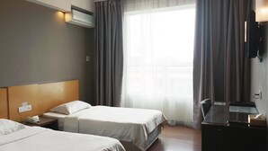 A hotel room with two beds, a desk, a TV, and an air conditioning unit. - LA Hotel Tawau (Tawau)