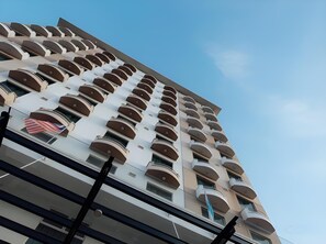 A high-rise building with multiple balconies, a clear sky, and a visible American flag. - LA Hotel Tawau (Tawau)
