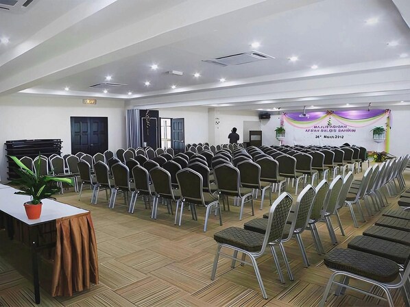 A conference room with rows of chairs, a stage, and a banner.