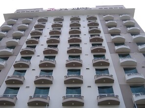 Ein mehrstöckiges Hotel mit einheitlicher Fassade, zahlreichen Balkonen und einem zentralen Eingang.