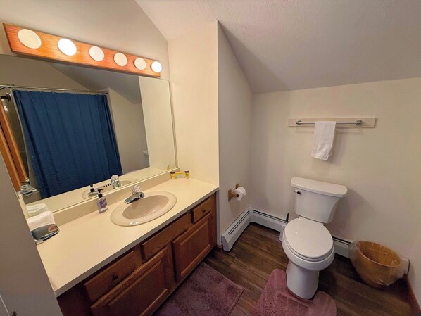 Un baño con lavamanos, espejo, inodoro y toallero.