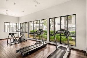 A gym with treadmills and elliptical machines, large windows with a view of buildings and greenery. - Puchong Setiawalk Penthouse for 14 Pax Iconique (Puchong)