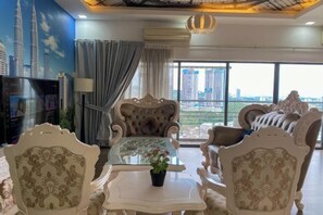 A spacious living room with ornate furniture, a glass coffee table, and a large window offering a city view. - Puchong Setiawalk Penthouse for 14 Pax Iconique (Puchong)