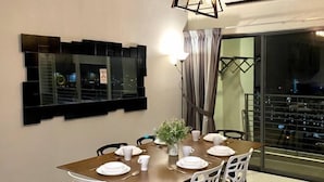 Un coin repas avec une table dressée pour quatre personnes, une plante décorative et un luminaire moderne.