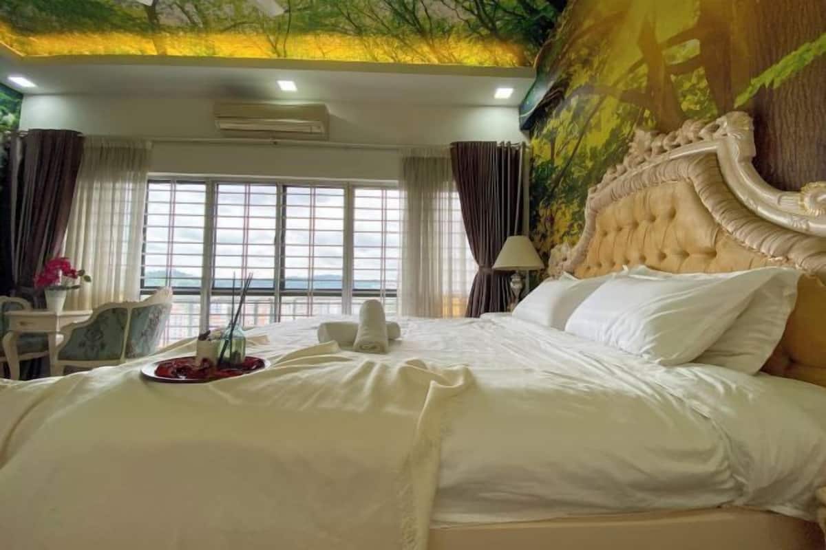 Una habitación de hotel con una cama grande, vista al mar por la ventana y un mural en la pared.