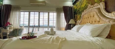 Una habitación de hotel con una cama grande, vista al mar por la ventana y un mural en la pared.