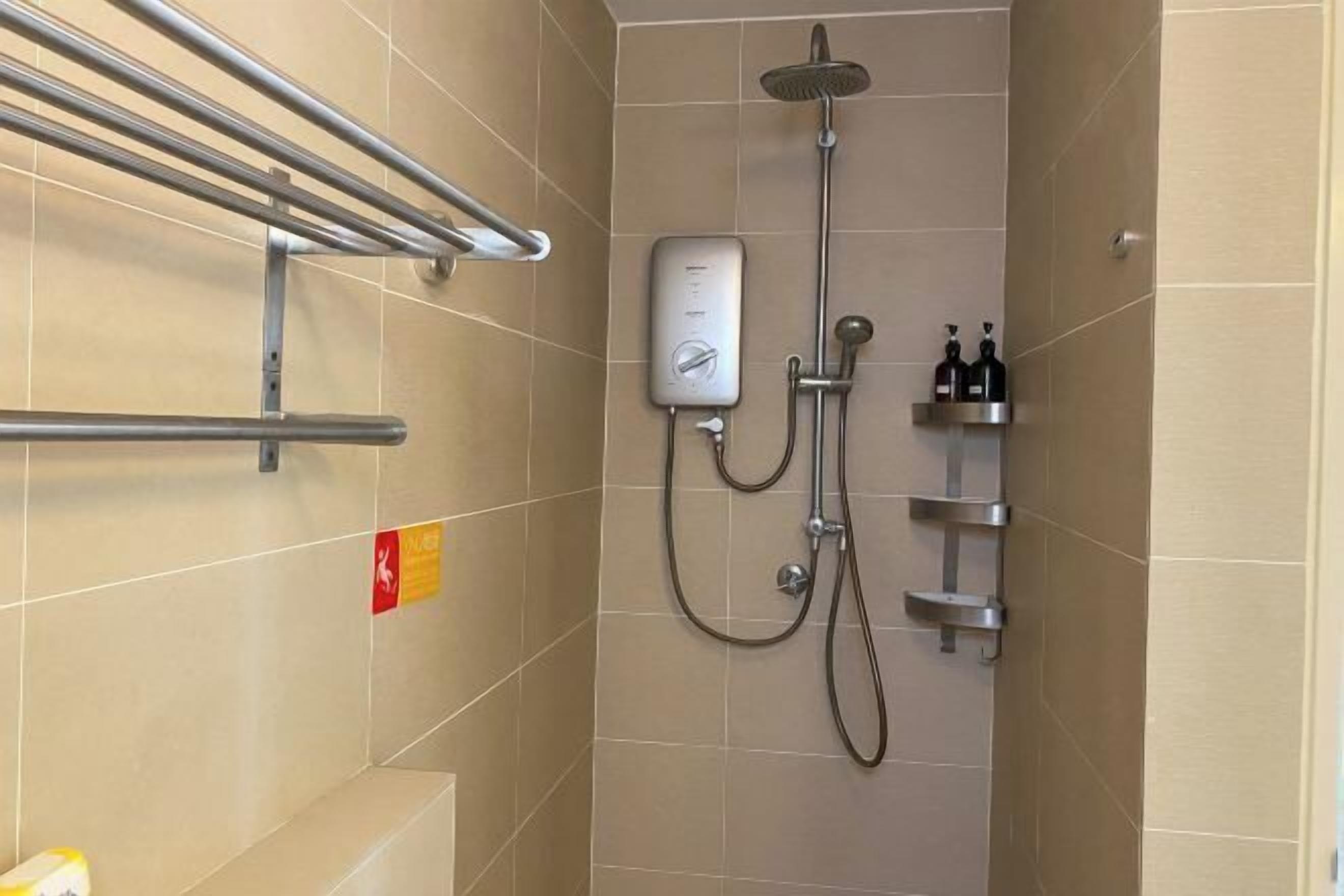 A shower area with a handheld showerhead, a wall-mounted control panel, and a shelf with toiletries.