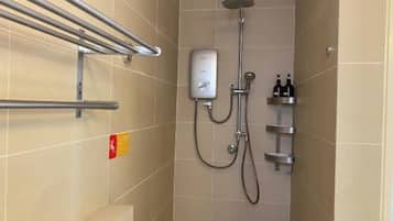 A shower area with a handheld showerhead, a wall-mounted control panel, and a shelf with toiletries.