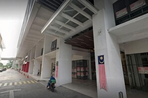 A building entrance with a flag, a covered area, and a person on a bicycle. - Da Men Subang Jaya USJ by Iconique (Subang Jaya)