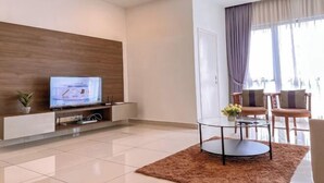 Een moderne woonkamer met een flatscreen televisie, een glazen salontafel en een zithoek.