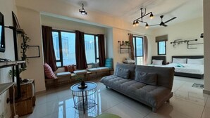 Een moderne woonkamer met een bank, een ronde salontafel en een bed met hoofdeinde.