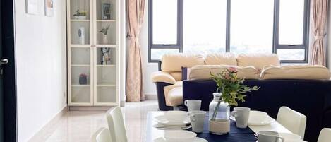 A dining area with a table set for four, a sofa in the background, and a cabinet with glass doors.