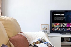 A living room with a television displaying 'Stranger Things' on Netflix, a magazine on the couch, and a framed picture on the table. - Da Men Subang Jaya USJ by Iconique (Subang Jaya)