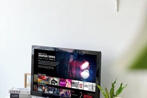 A flat-screen TV displaying a Netflix interface with 'Stranger Things' prominently featured.