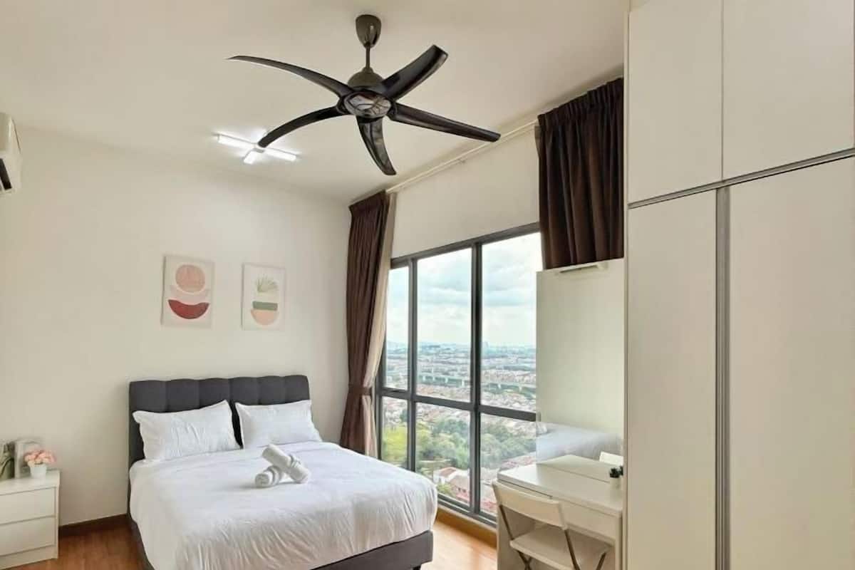 Ein Schlafzimmer mit Bett, Schreibtisch, Deckenventilator und großem Fenster mit Blick.