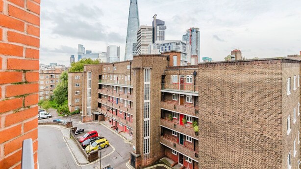A multi-story brick building with a courtyard, featuring a red car and a yellow car parked in front. - Sleek Southwark 2BR, Furniture & Decor Included, by Blueground (London)