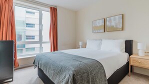 A hotel room with a large bed, a TV, and a window with curtains. - Sleek Southwark 2BR, Furniture & Decor Included, by Blueground (London)